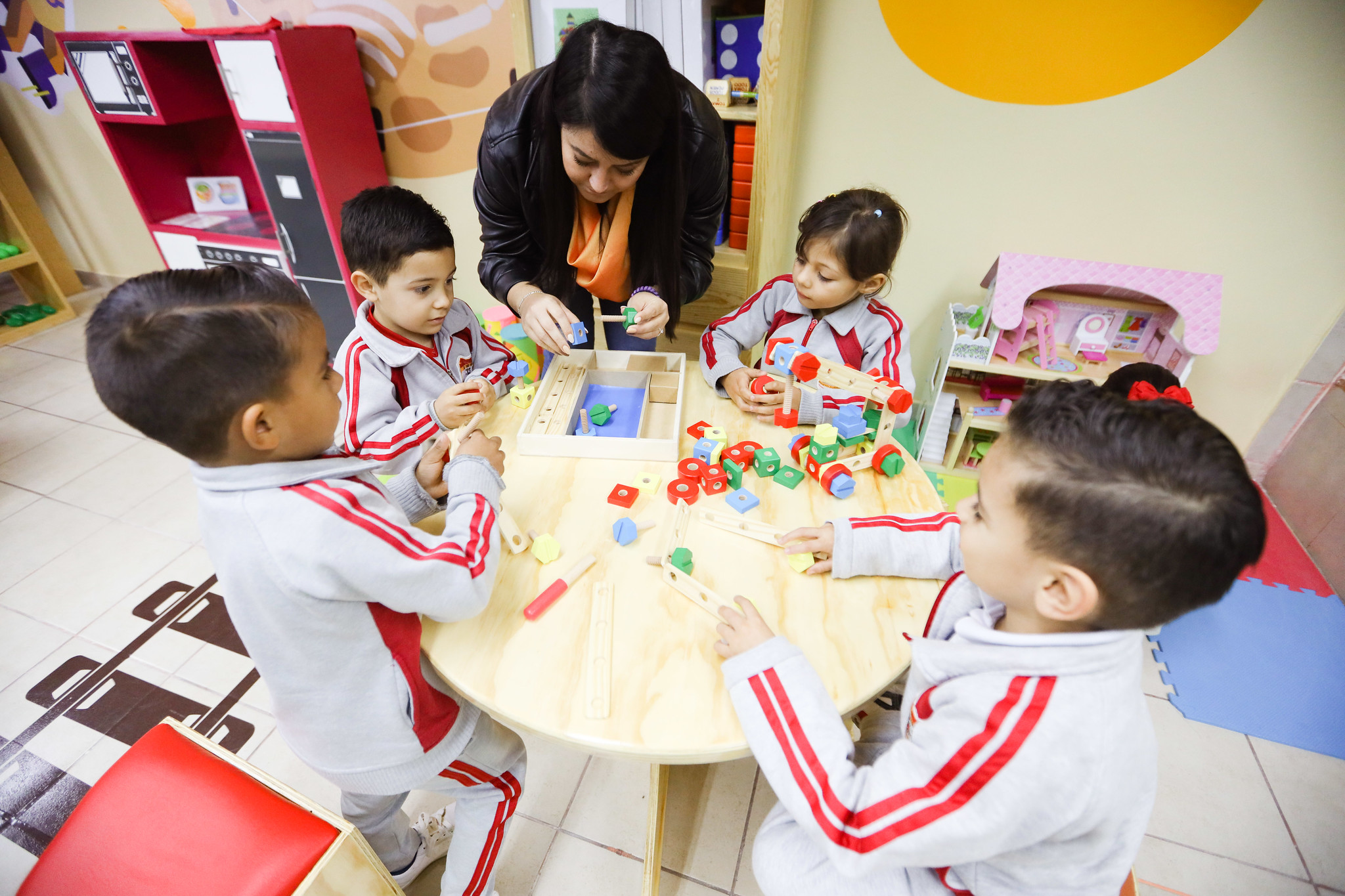 Niños jugando en materiales de destreza con guía de maestra